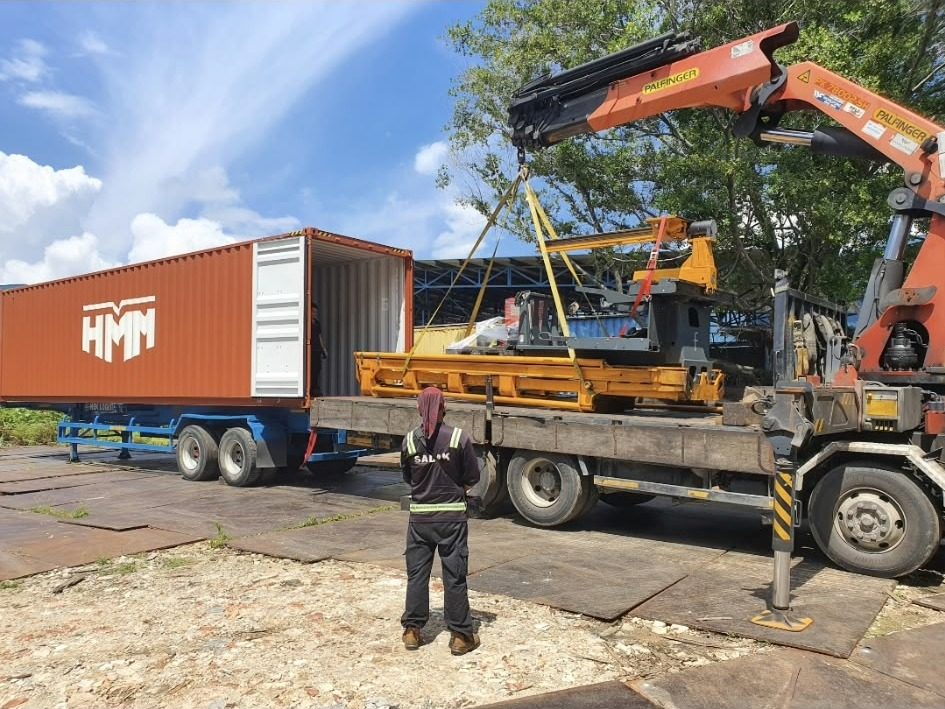 Crane loading a forklift into a container