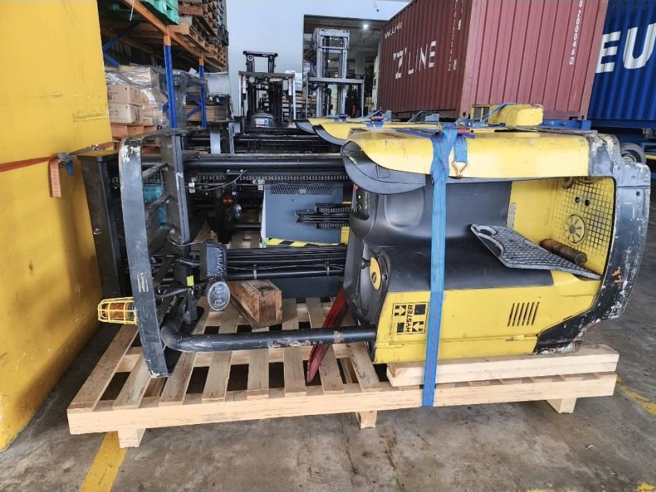 Forklift secured on a pallet beside a container
