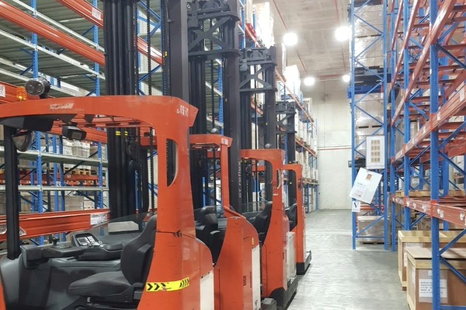 Toyota reach trucks in a warehouse aisle beside tall pallet racking
