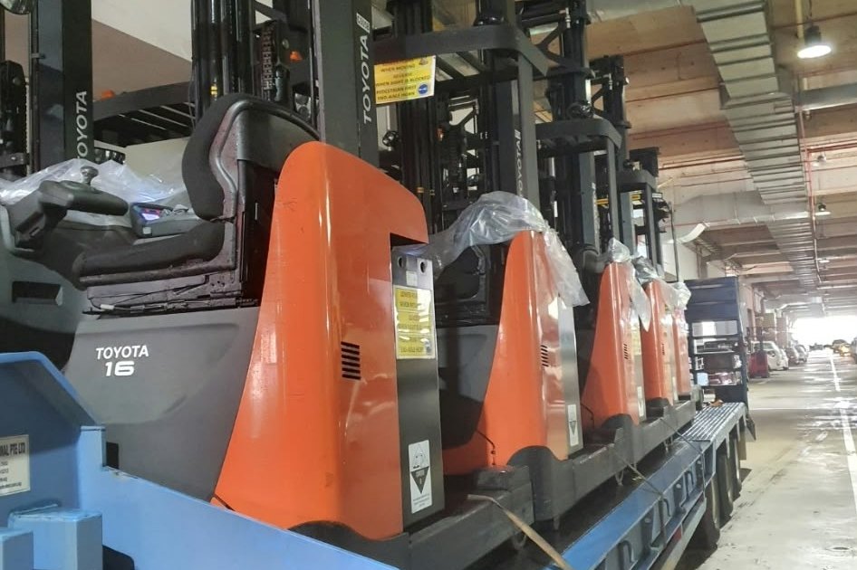 Toyota reach trucks strapped onto a low-bed trailer for relocation