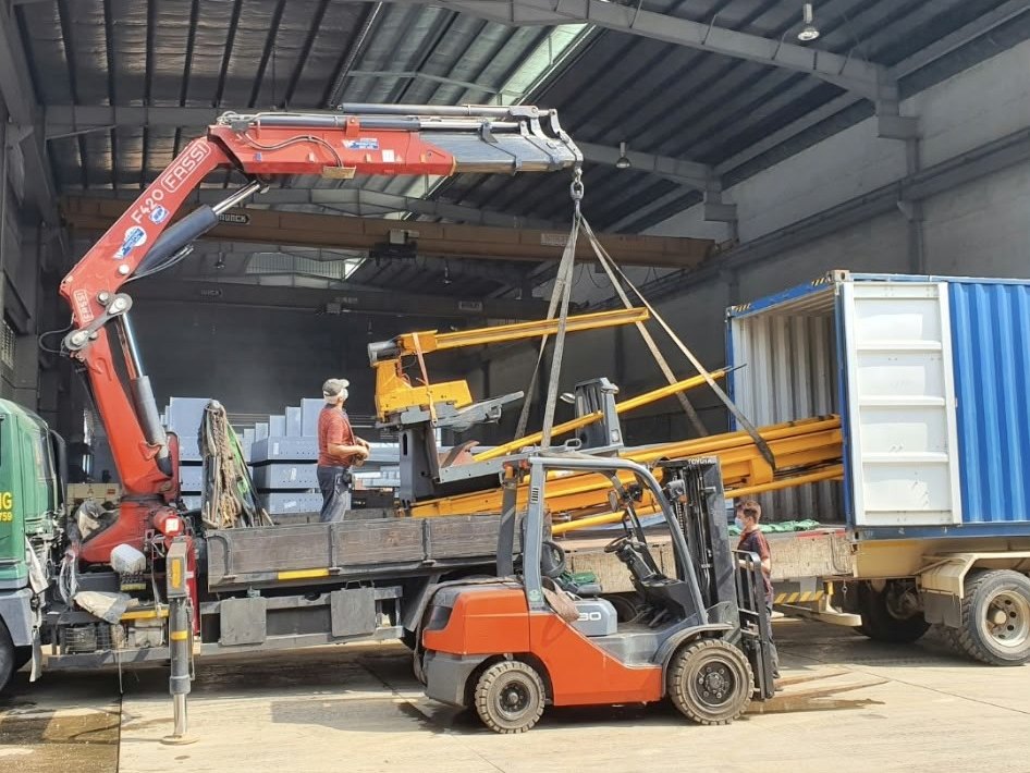 Crane loading a forklift into a shipping container