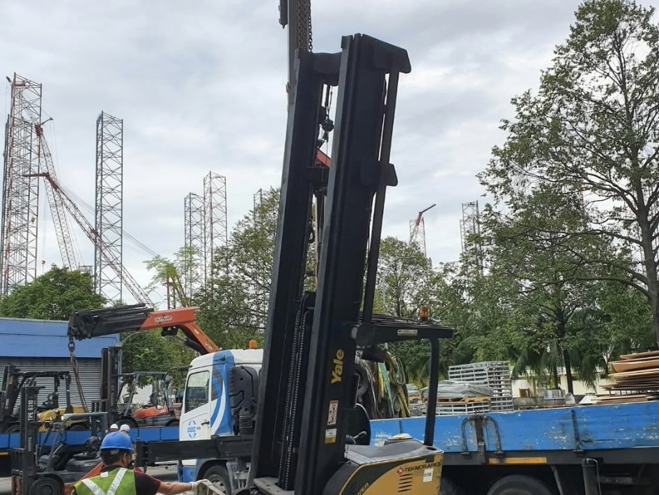 High-mast reach truck being lifted by crane for relocation